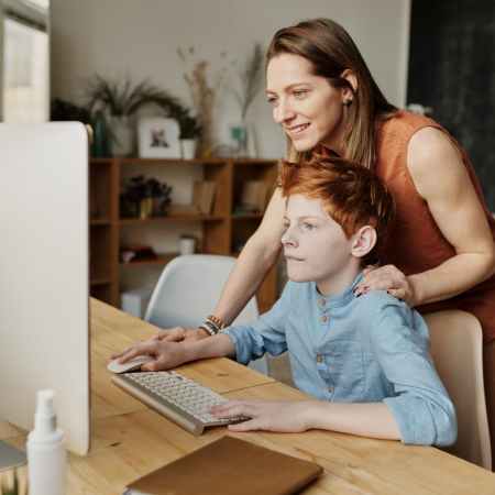 photo of woman and boy looking at imac