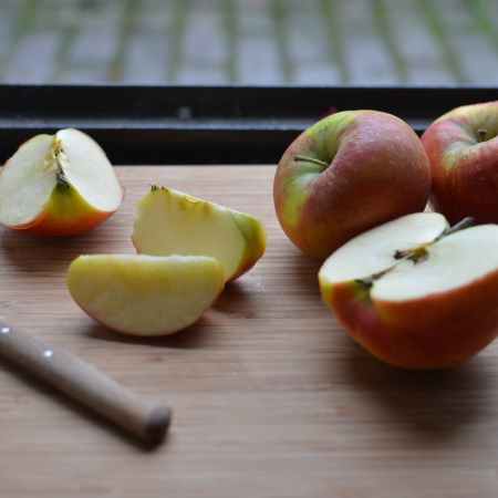 board with slices of fresh apples and knife near window