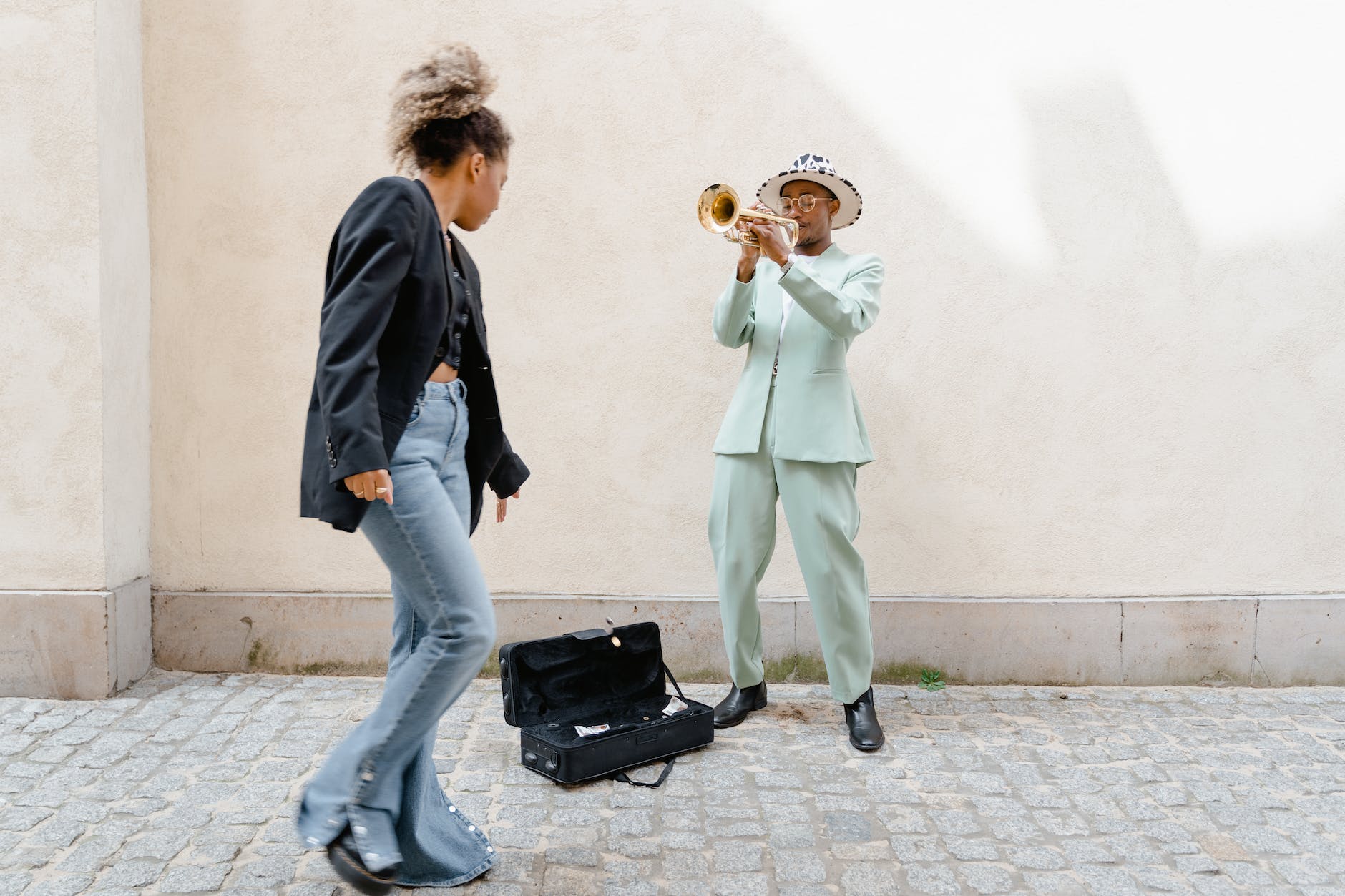woman giving coins to the man playing trumpet