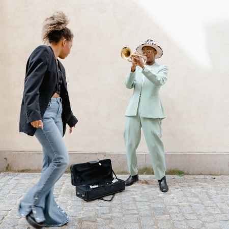 woman giving coins to the man playing trumpet